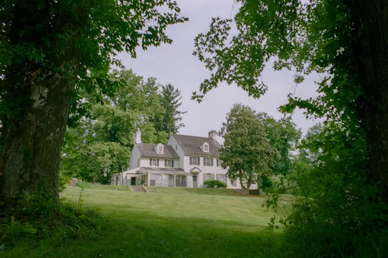 A house on a grassy lot surrounded by mature trees
